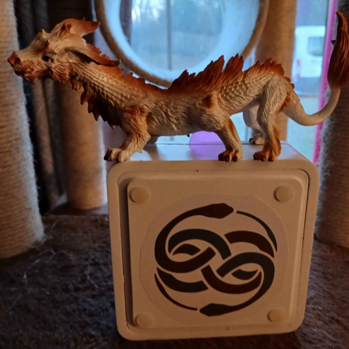 A decorative luckdragon figurine perched on a square base with the Auryn symbol from The Never-Ending Story.